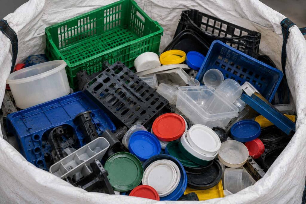 Material de polipropileno PP reciclable compuesto por canastillas, tapas, recipientes y componentes plásticos industriales almacenados para reciclaje en Bogotá.